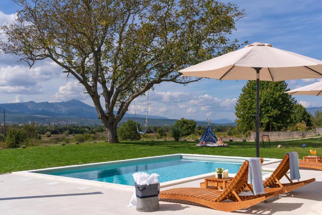 a swimming pool with two chairs and an umbrella at 2-bedroom Villa Providenca in Bajagić