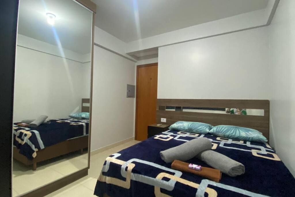 - une chambre avec un miroir et un lit avec des oreillers dans l'établissement Apartamento Inteiro - 2 Quartos com AC - Wifi 300mb - Cozinha Completa - 1 Vaga de Garagem - TV Smart 50 - Sacada - Indicado para Grupos, Hospedes a Trabalho, Família e Pets, à Toledo