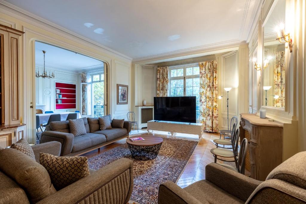 a living room with couches and a flat screen tv at Avenue Niel - Appart spacieux in Paris