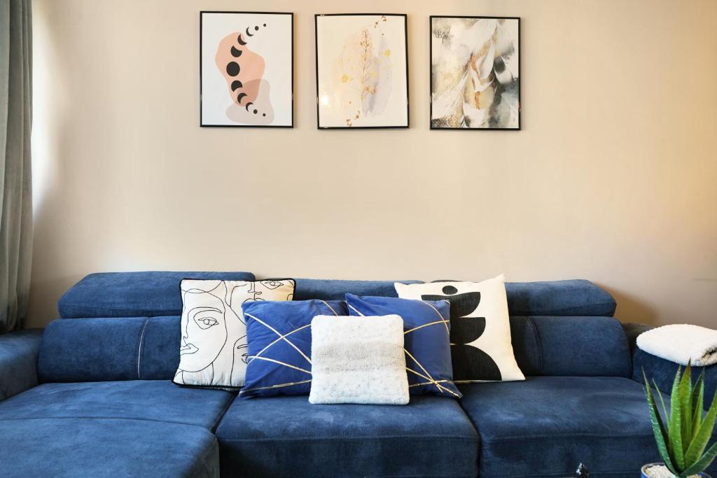 eine blaue Couch mit Kissen in einem Wohnzimmer in der Unterkunft Elegant 2BR Aylesbury Home, Sleeps 4, Parking, Work, Leisure, Friendly in Buckinghamshire