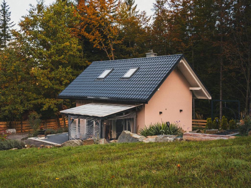 ein kleines Haus mit Solardach auf einem Feld in der Unterkunft Domek Pierwiosnek Ustroń - cisza, las, balia i totalny relaks - Ucieknij od zgiełku i poczuj spokój natury in Ustroń