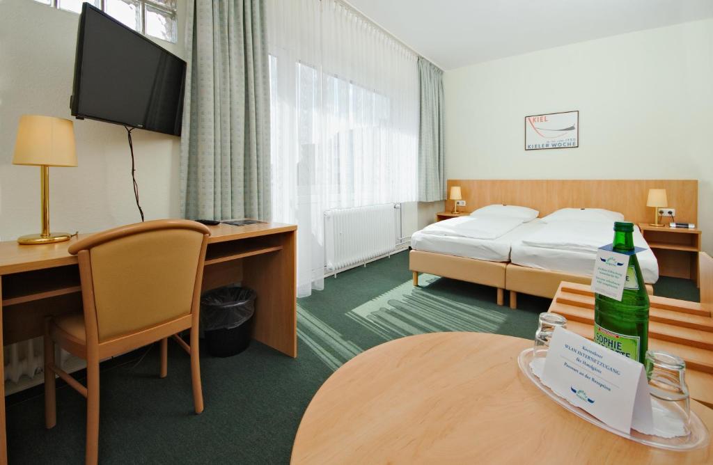 ein Hotelzimmer mit einem Bett und einer Flasche auf dem Tisch in der Unterkunft Hotel Wiking in Kiel