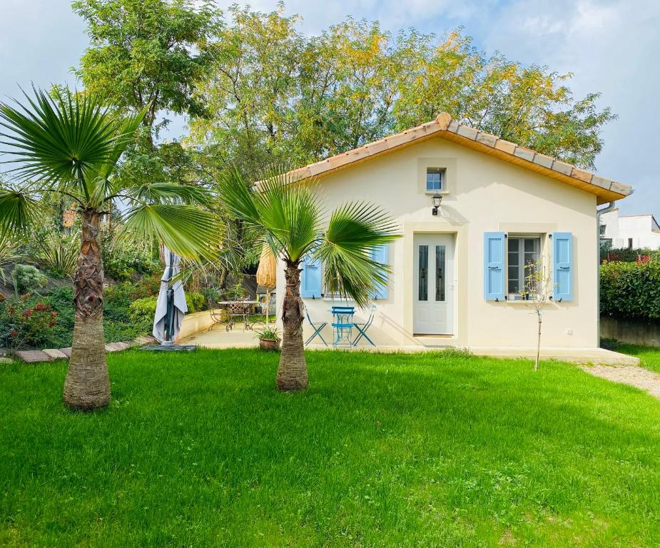 une petite maison avec deux palmiers dans la cour dans l'établissement Le Saint Marin, à Chatuzange-le-Goubet