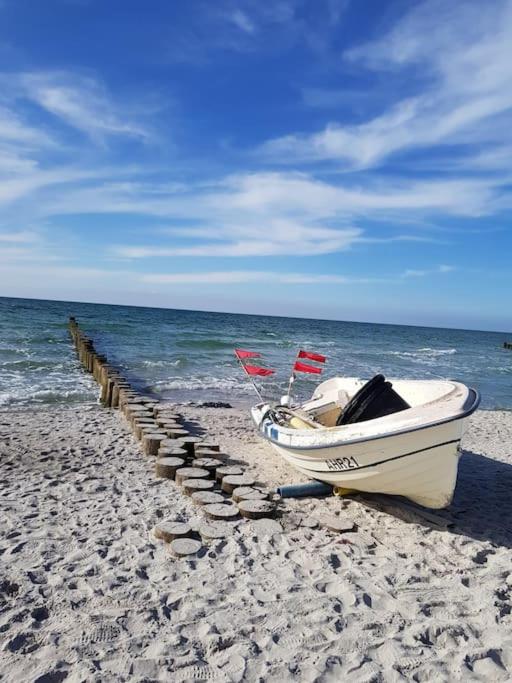 a boat sitting on a beach next to the ocean at Modernes Appartement mit Meerblick in Ahrenshoop