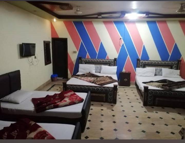 a room with three beds and a colorful wall at New Faizan Hotel in Lahore