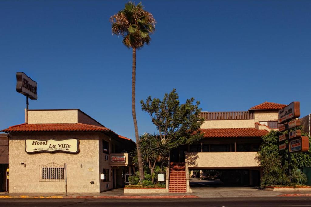 a palm tree in front of a building with a sign at La Villa de Zaragoza in Tijuana