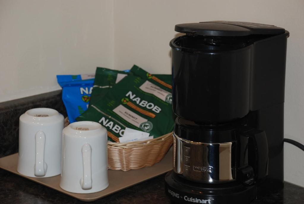 a coffee maker and two cups on a counter at Rideau Heights Inn in Ottawa