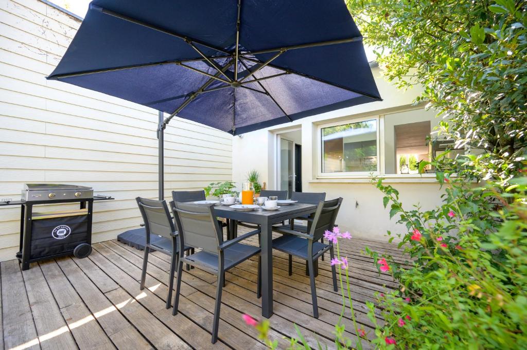 une table avec des chaises et un parasol sur une terrasse dans l'établissement Villa Marcel, LE CHARME à 10 min à pied du centre, à La Rochelle