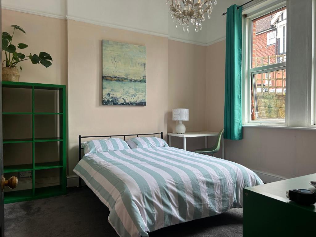 a bedroom with a bed and a window and a chandelier at Bohemian Rhapsody in St. Leonards