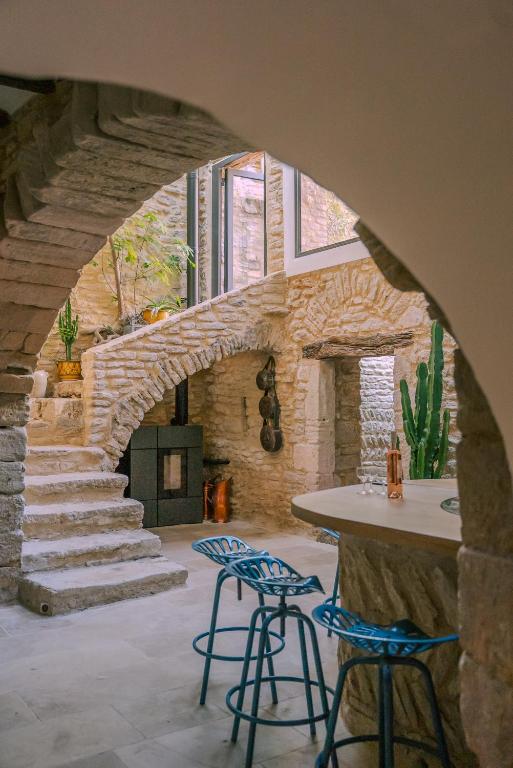 une arcade avec deux tabourets et un comptoir dans une pièce en pierre dans l'établissement Grande maison de charme au coeur de Goult, à Goult