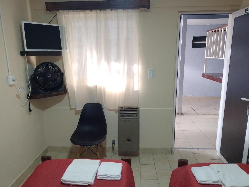 a room with two beds and a chair and a window at Hotel Parque in Villa Mercedes