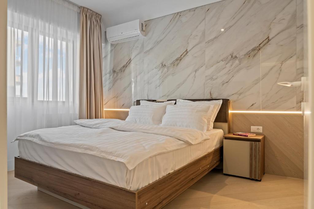 ein Schlafzimmer mit einem großen Bett mit einer Marmorwand in der Unterkunft Apartament Luxury Cortina North Residence Pipera in Voluntari