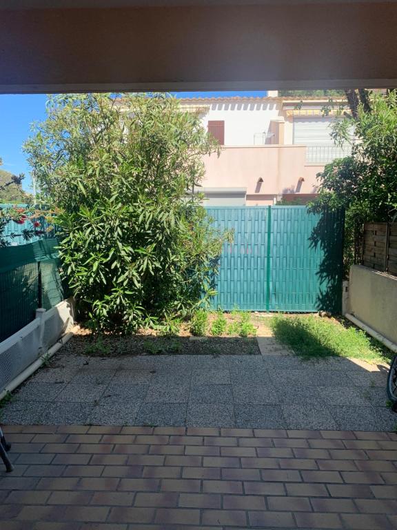 a gate with a bush in front of a fence at Slyre in Cap d'Agde