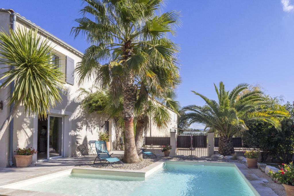 - une piscine bordée de palmiers en face d'une maison dans l'établissement Source de Vie, à Noves