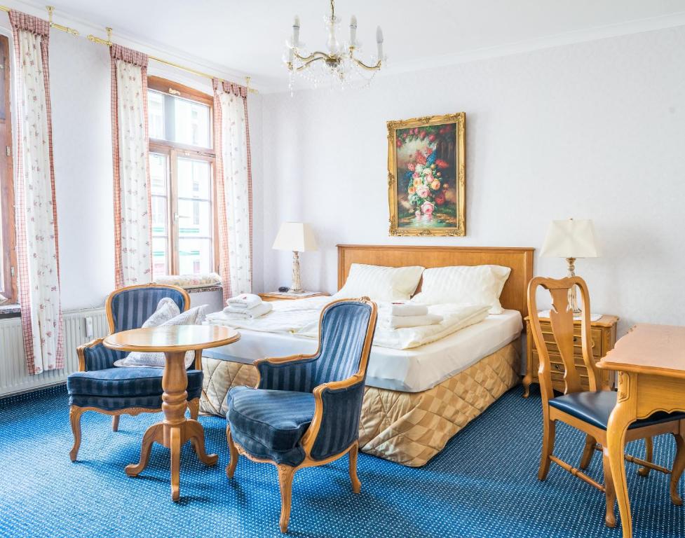 シュヴェリーンにあるRomantisches Hotel Zur Traube Schwerinのベッド、テーブル、椅子が備わるホテルルームです。