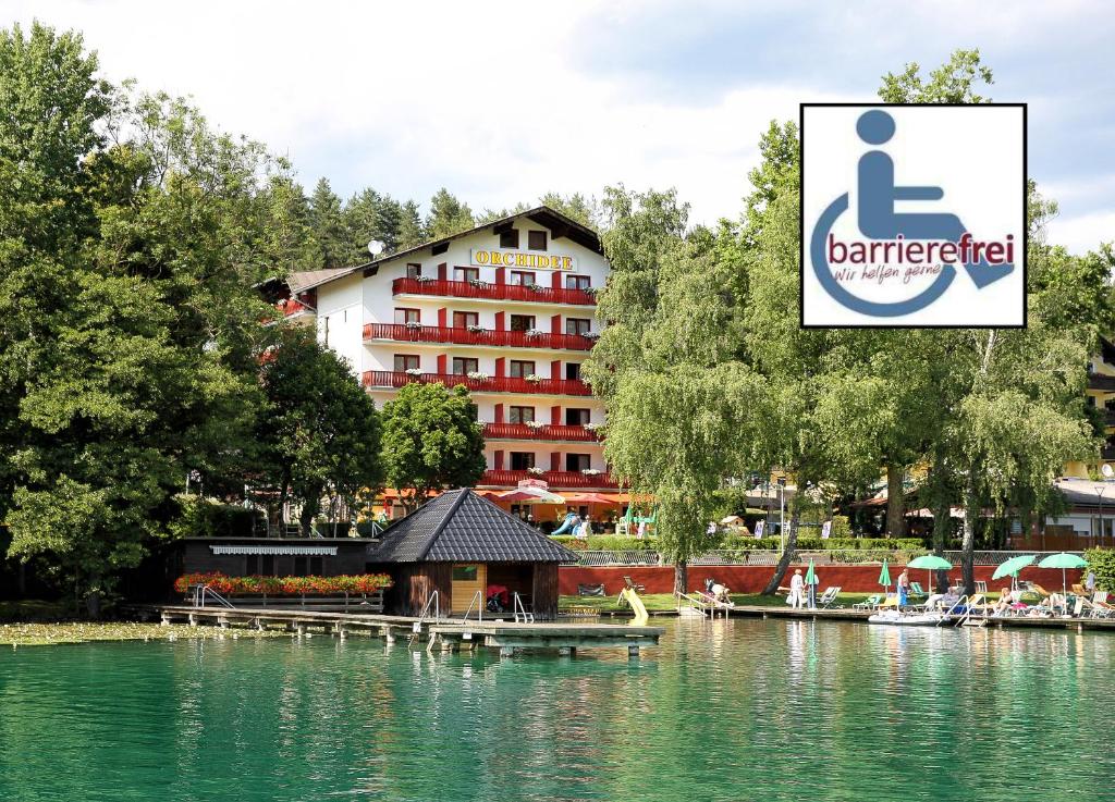 een hotel en een meer met een prieel op de voorgrond bij Strandhotel Orchidee in Sankt Kanzian