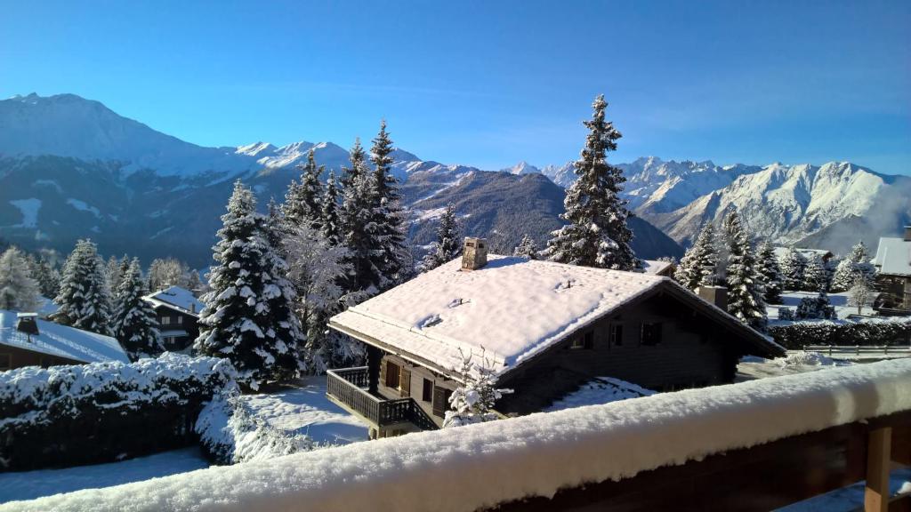 ein schneebedecktes Haus mit Bergen im Hintergrund in der Unterkunft Rodasia in Verbier