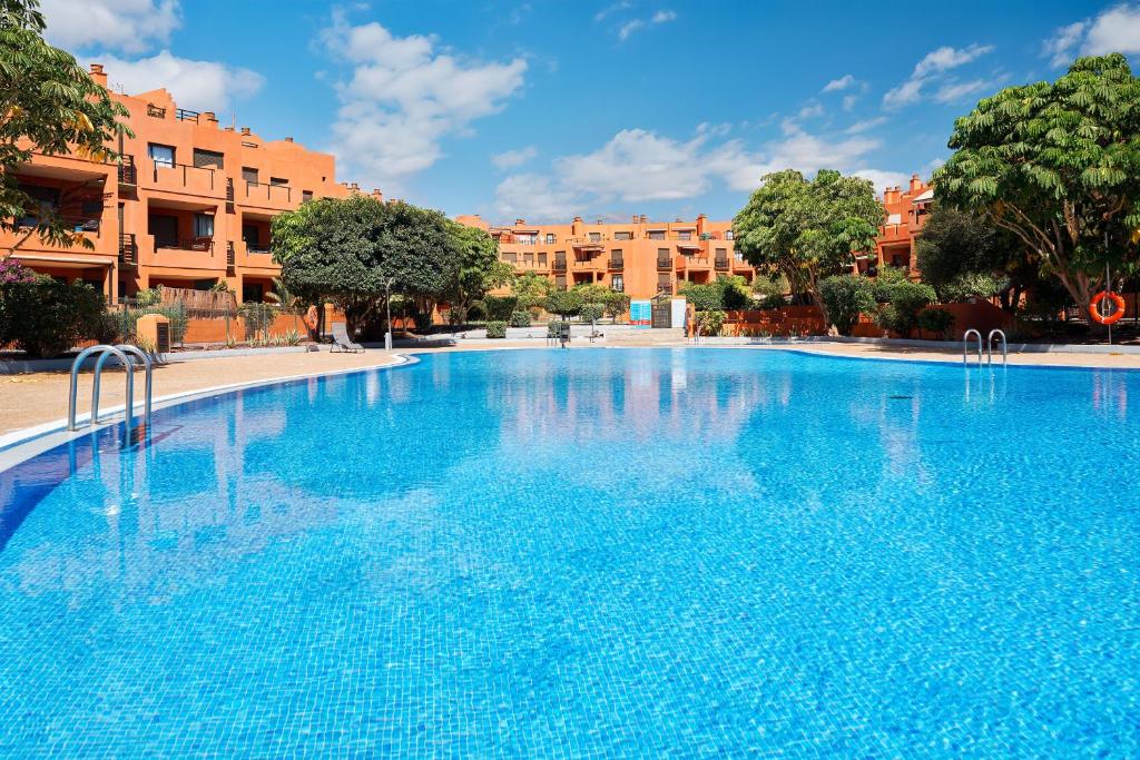a large blue swimming pool with buildings in the background at Garden Suite in Granadilla de Abona