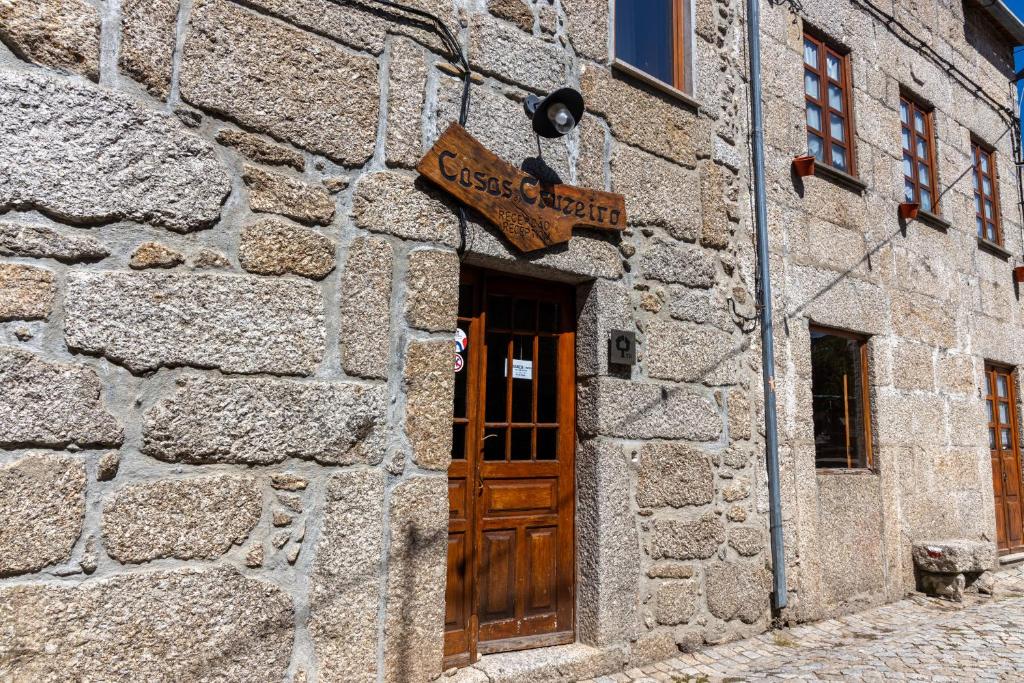 a stone building with a door and a sign on it at Casas do Cruzeiro in Sabugueiro