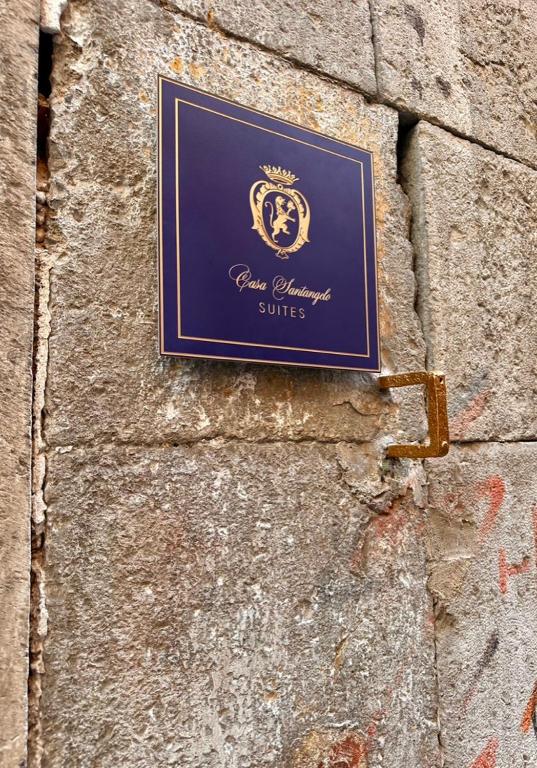 a sign on the side of a stone wall at Casa Santangelo Suites in Salerno