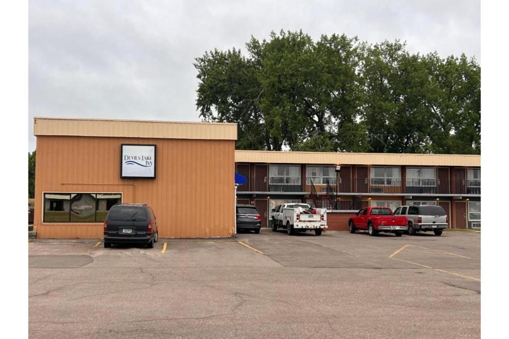 a building with cars parked in a parking lot at Devils Lake Inn By OYO Near Devils Lake Regional Airport in Devils Lake