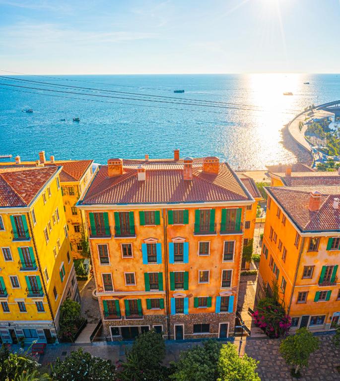 a group of yellow buildings next to the ocean at Thala Hotel Sorrento in Phú Quốc