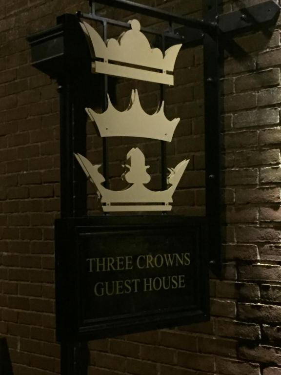 a sign for a three crowns guest house on a brick wall at Three Crowns Guest House in Salisbury