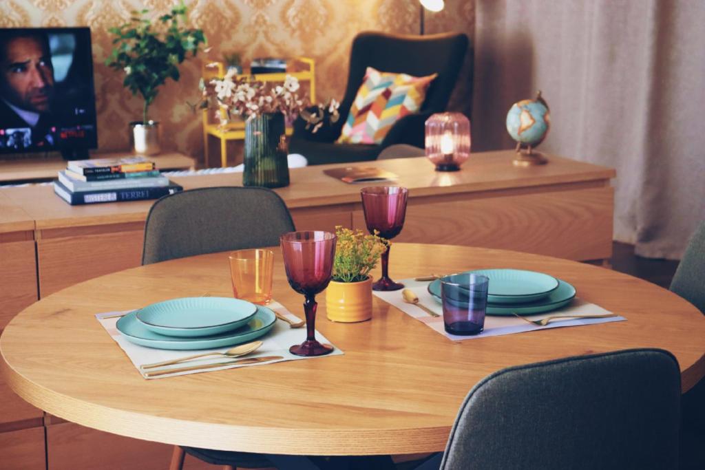 Una mesa de madera con platos y copas de vino encima. en FREE PARKING & Self Check-IN WestSide Studio Near the Lake, Lacul Morii,Near Metro Stations Sector6, en Bucarest