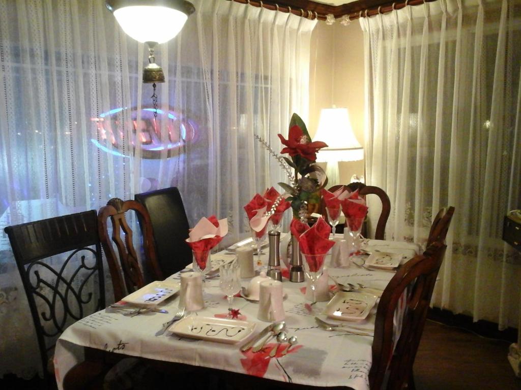 a dining room table with a white table cloth and red flowers at gite des iles in Matane
