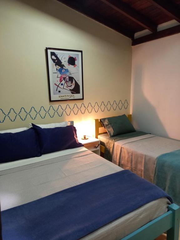 a room with two beds and a picture on the wall at Flat Duplex - Flat & Residence Premium in Campo Grande