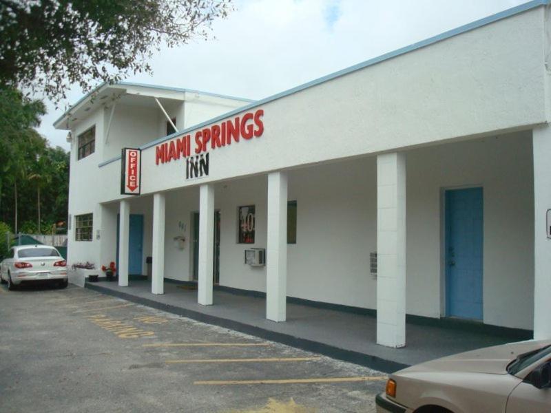 um grande edifício branco com um carro estacionado num parque de estacionamento em Miami Springs Inn em Miami
