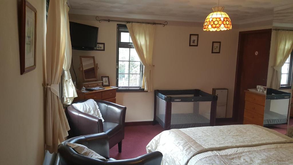 a bedroom with a bed and a desk and chairs at Kingfisher Cottage in Tavistock