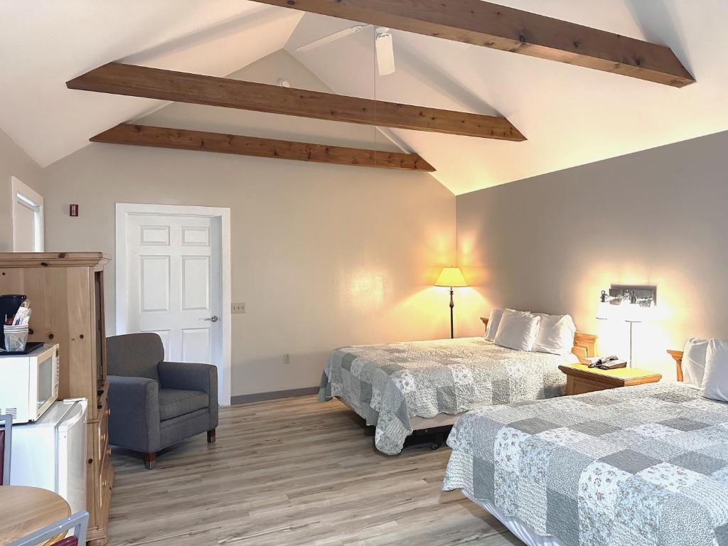 una habitación de hotel con dos camas y una silla en Spruce Lane Lodge and Cottages, en Smoketown