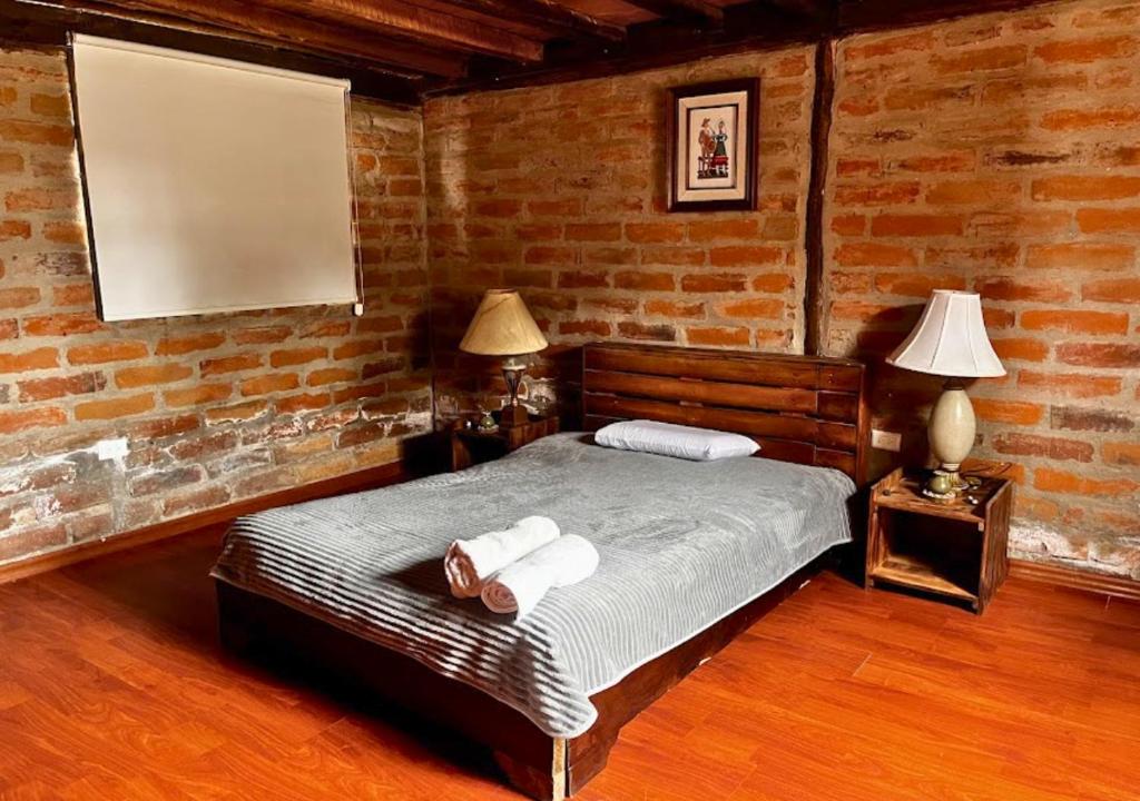 een slaapkamer met een bed in een bakstenen muur bij Cabaña en el Campo Malchinguí WIFI 24 horas in Malchinguí