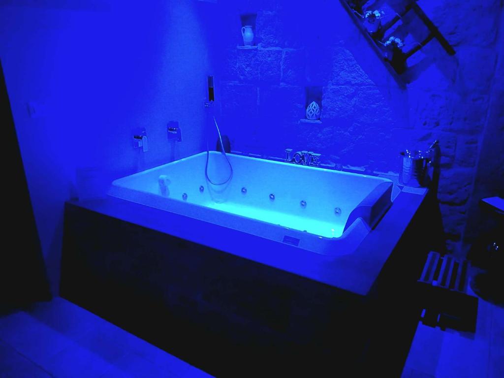 une salle de bain avec une baignoire blanche dans une lumière bleue dans l'établissement BELOVED luxury room, à Corato