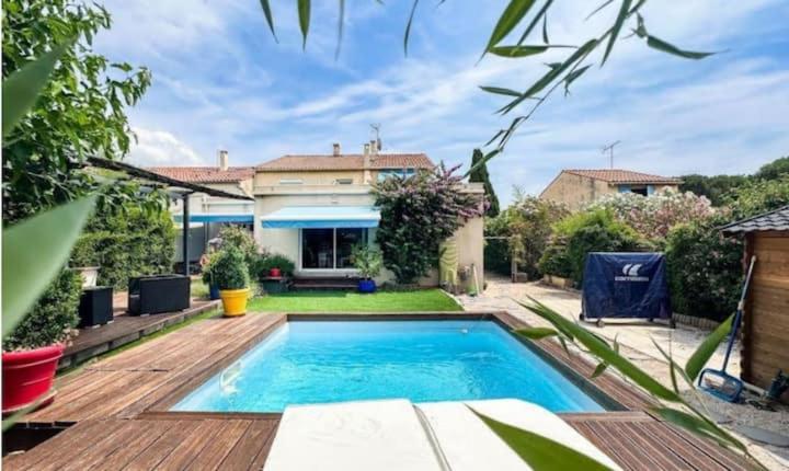 une cour arrière avec une piscine et une maison dans l'établissement Maison avec Jardin proche du tram, à Le Crès
