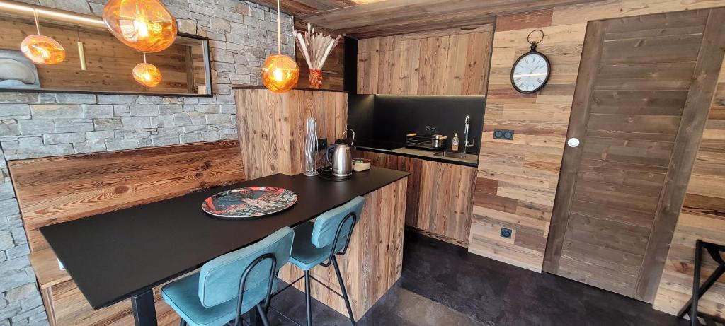 a kitchen with a black counter and blue chairs at Grands studios vue sur lac in Tignes