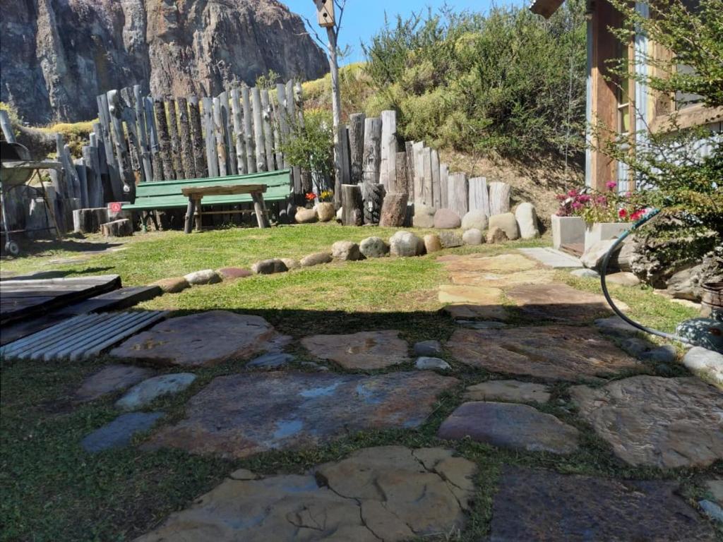 a garden with a green bench and a fence at Cabaña El Carpintero in El Chalten