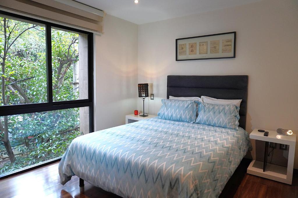 a bedroom with a bed and a large window at Magnífico departamento, muy bien ubicado. in Mexico City