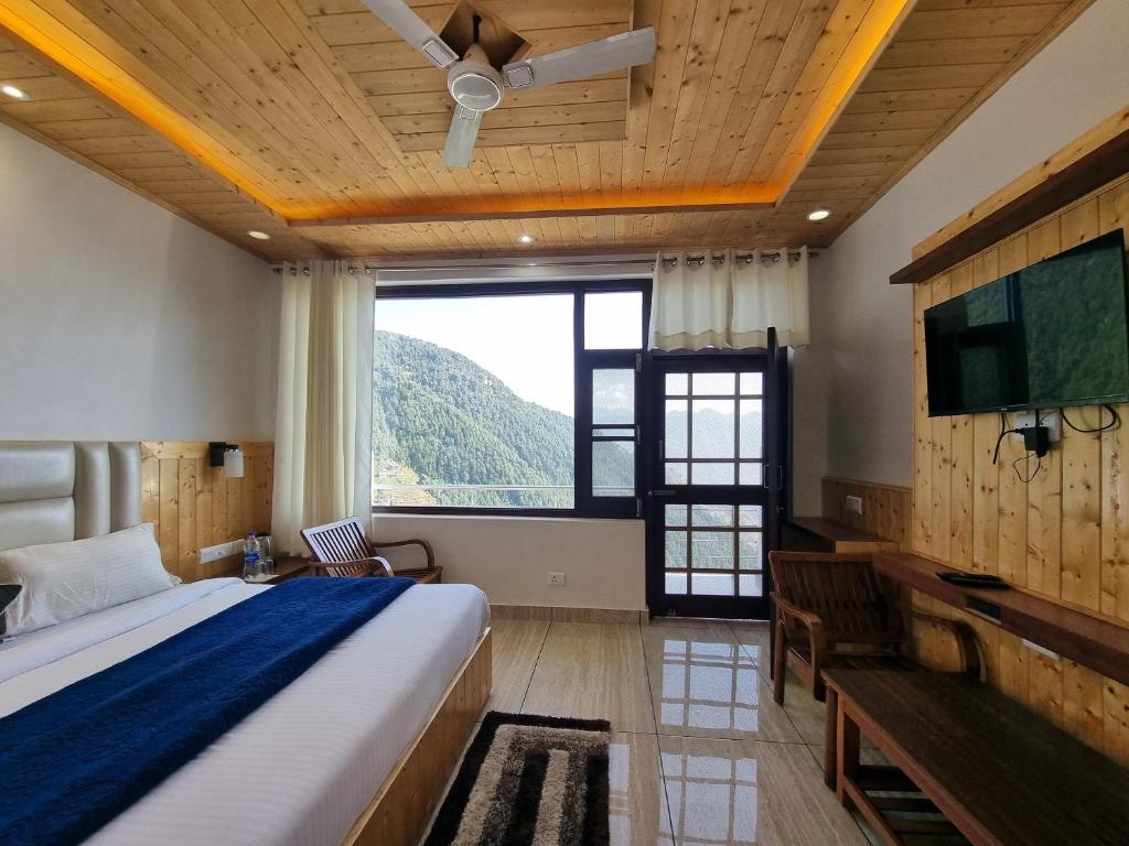 a bedroom with a bed and a flat screen tv at Grand Kailash Khajjiar in Dalhousie