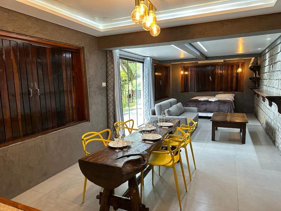 a living room with a table and yellow chairs at Apto 10, Temático Veuve Clicquot com Jacuzzi na Morada do Ganso in Bombinhas