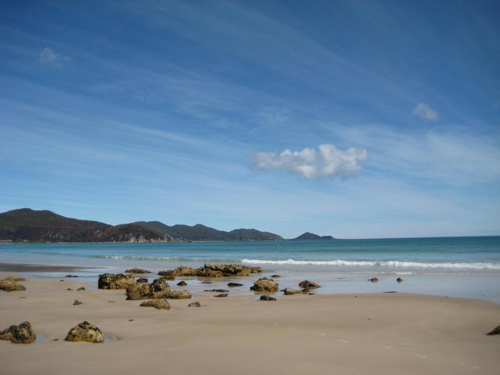 una playa con rocas en la arena y el océano en Sisters Beach House, en Sisters Beach