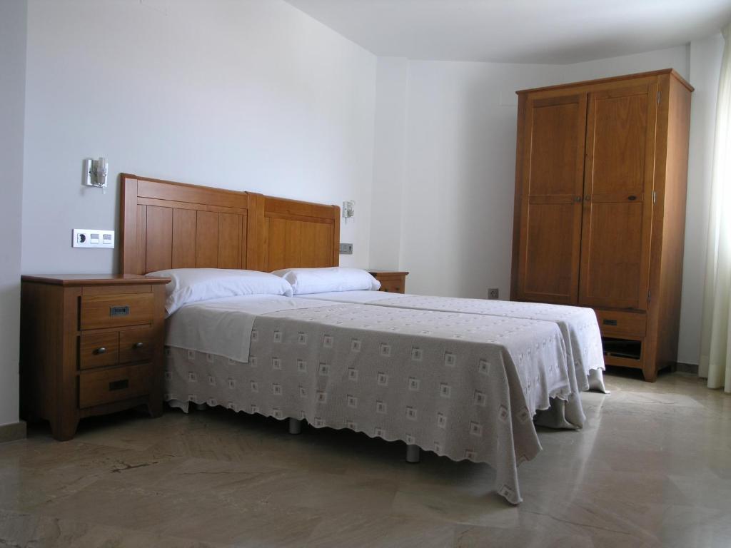 1 dormitorio con 1 cama grande y armario de madera en Apartamentos Aixa II, en Caravaca de la Cruz