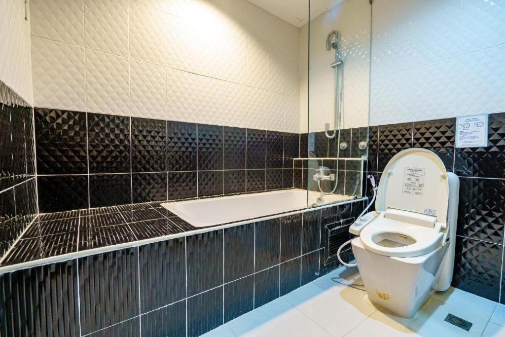 a bathroom with a toilet and a bath tub at Sakura Sky Residence in Bangkok