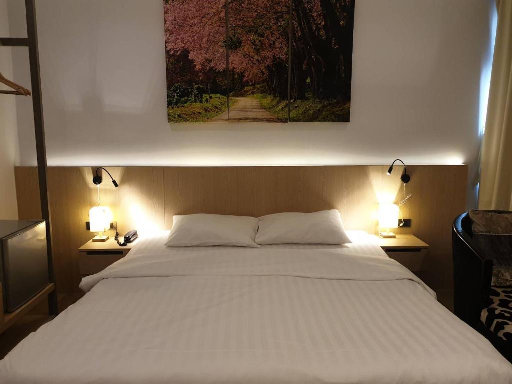 a bedroom with a large white bed with two lamps at Sakura Sky Residence in Bangkok
