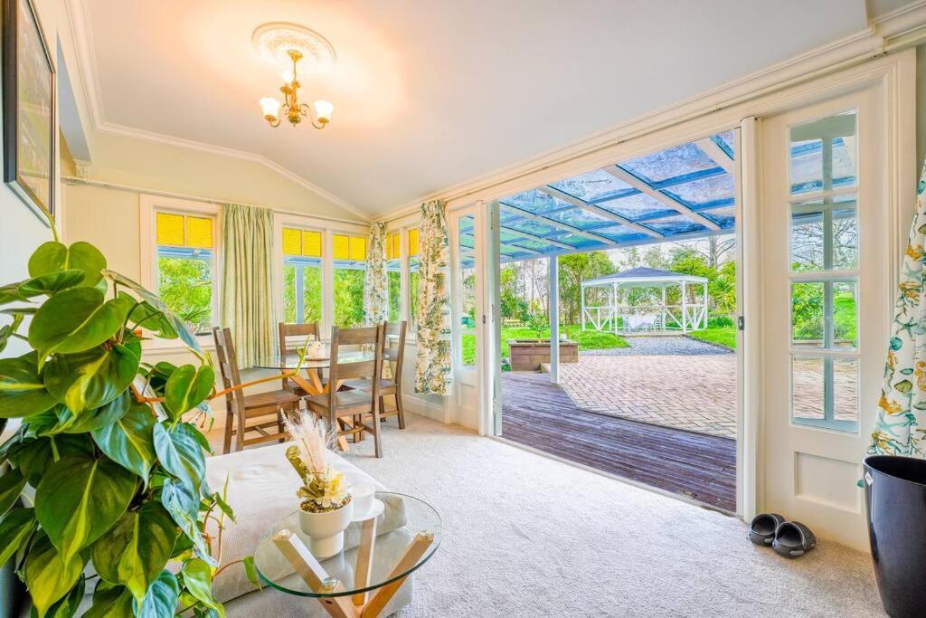 - un salon avec une porte en verre, une table et des chaises dans l'établissement Horse Club Retreat 3 Bedrooms, à Dairy Flat