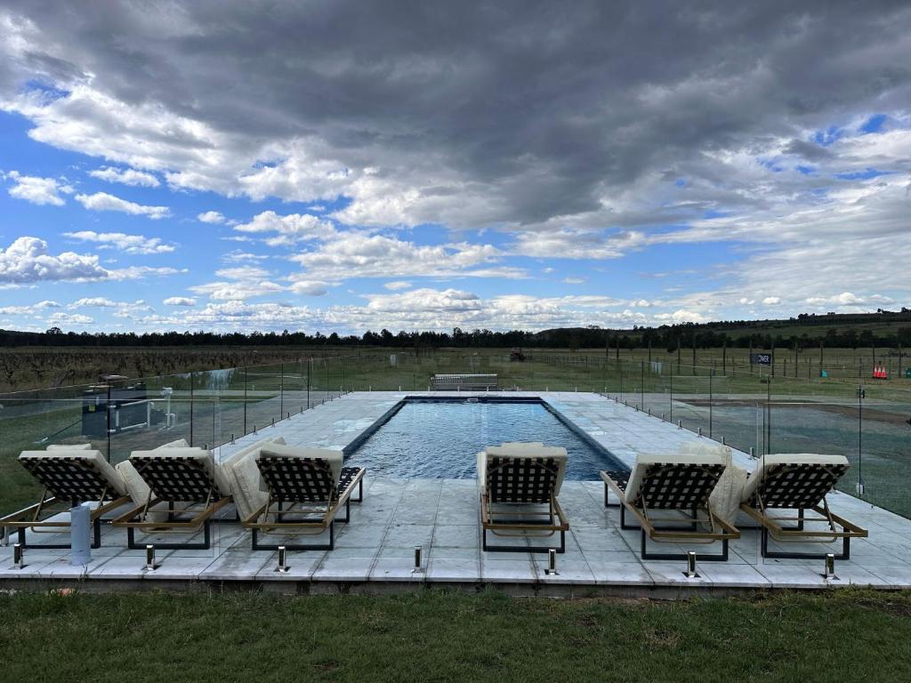 a group of chairs sitting around a swimming pool at Soldiers Cottage picturebook vineyard home in Bulga