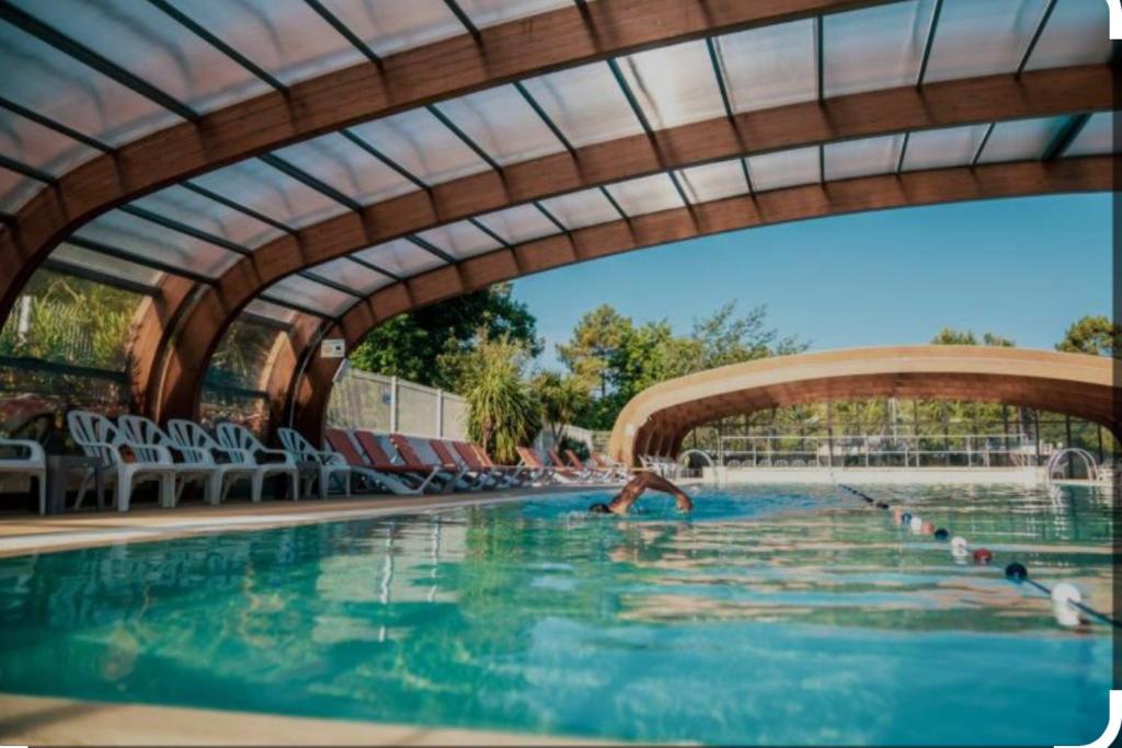 une personne se baignant dans une piscine sous un pont dans l'établissement Mobile home cocon, à Lège-Cap-Ferret