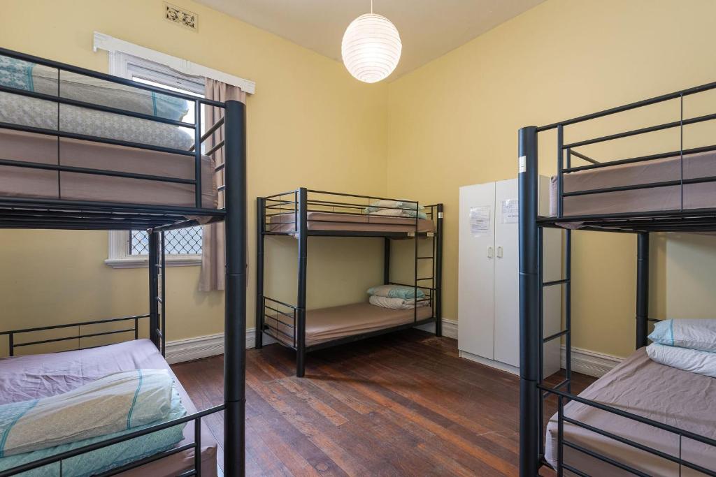 a room with three bunk beds and a hallway at 1849 Backpackers Albany in Albany
