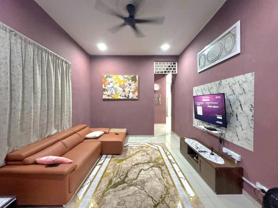 Il comprend un salon doté d'un canapé brun et d'une télévision à écran plat. dans l'établissement Norelsya Homestay Bemban Melaka, à Bemban